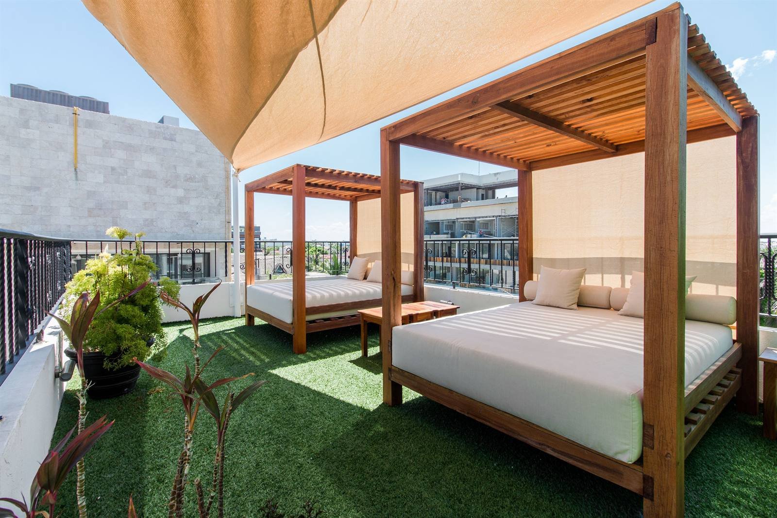 Suites Corazón: rooftop terrace with wooden daybeds and a large sunshade